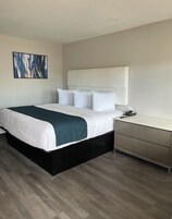 Una habitación de hotel moderna con una cama grande, una mesita de noche y un escritorio.