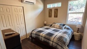 A bedroom with a bed, a ceiling fan, a window, and a dresser. - Calypso's Hideaway in delightful Pine with WiFi, AC (Pine)