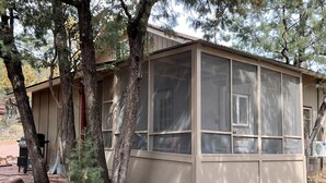 A building with a large window, surrounded by trees and a gravel path. - Calypso's Hideaway in delightful Pine with WiFi, AC (Pine)