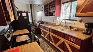 A compact kitchen with a stove, sink, and wooden cabinets. - Calypso's Hideaway in delightful Pine with WiFi, AC (Pine)