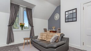 Un salón moderno con un sofá de cuero gris, una mesita redonda y una alfombra gris.