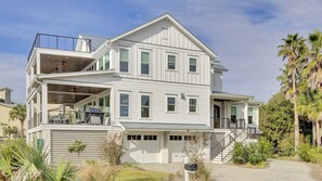 A multi-story house with a covered patio, a garage, and a landscaped garden.