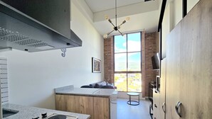 A modern kitchen with a central island, a built-in stove, and a large window offering a view of the outdoors. - Atelier Cedritos by Weeki. (Bogotá)