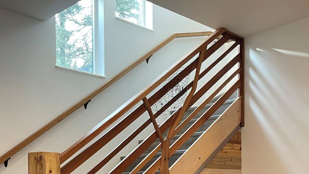 A wooden staircase with a glass railing, a wooden stool, and a cabinet. - Tiny Retreat at Stoney Creek  (Seward)
