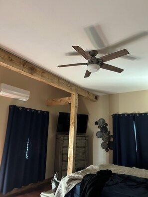 Relax in this serene bedroom with a ceiling fan, air conditioning unit, and comfortable bed.