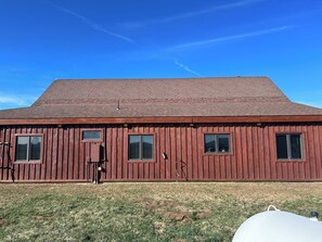 Situated on a grassy area, this rustic barn features a sloped roof and windows along its side.