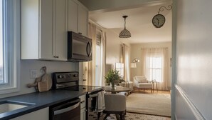 A modern kitchen with a built-in oven, a microwave, and a dining area with a chair and a table. - Kellys Suite (Geneva)