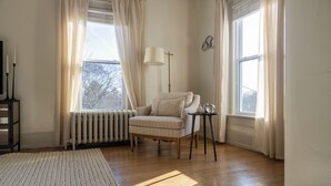 A cozy room with a radiator, a chair, a small table, and a window with curtains. - Kellys Suite (Geneva)