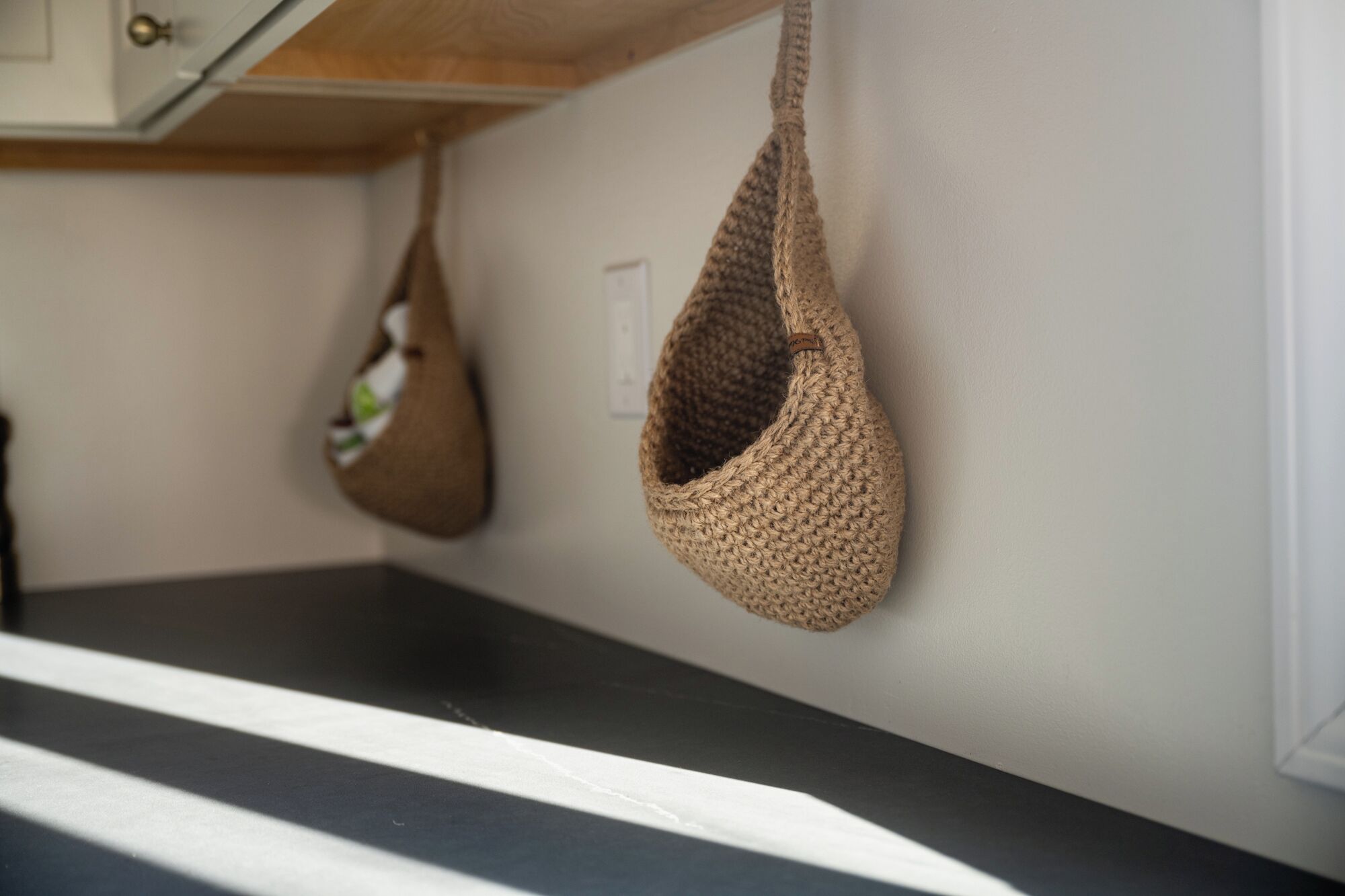 A kitchen with a black countertop and two hanging bags.