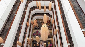 Un vaste atrium doté d’un espace de détente central, de plusieurs luminaires suspendus et d’un sol à motifs.