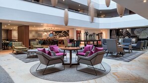 Un hall d’entrée spacieux, doté d’un haut plafond, de meubles modernes et d’un espace salon central.