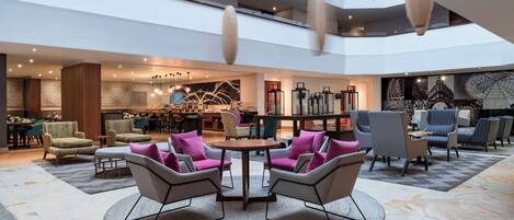 A spacious lobby with a high ceiling, modern furniture, and a central seating area.