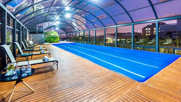 Un espace piscine couvert avec des chaises longues et une terrasse en bois.