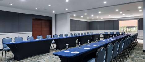 A conference room with a long table, chairs, and a view of the outdoors.