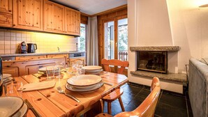 A cozy kitchen with wooden cabinets, a dining table set for four, and a fireplace.