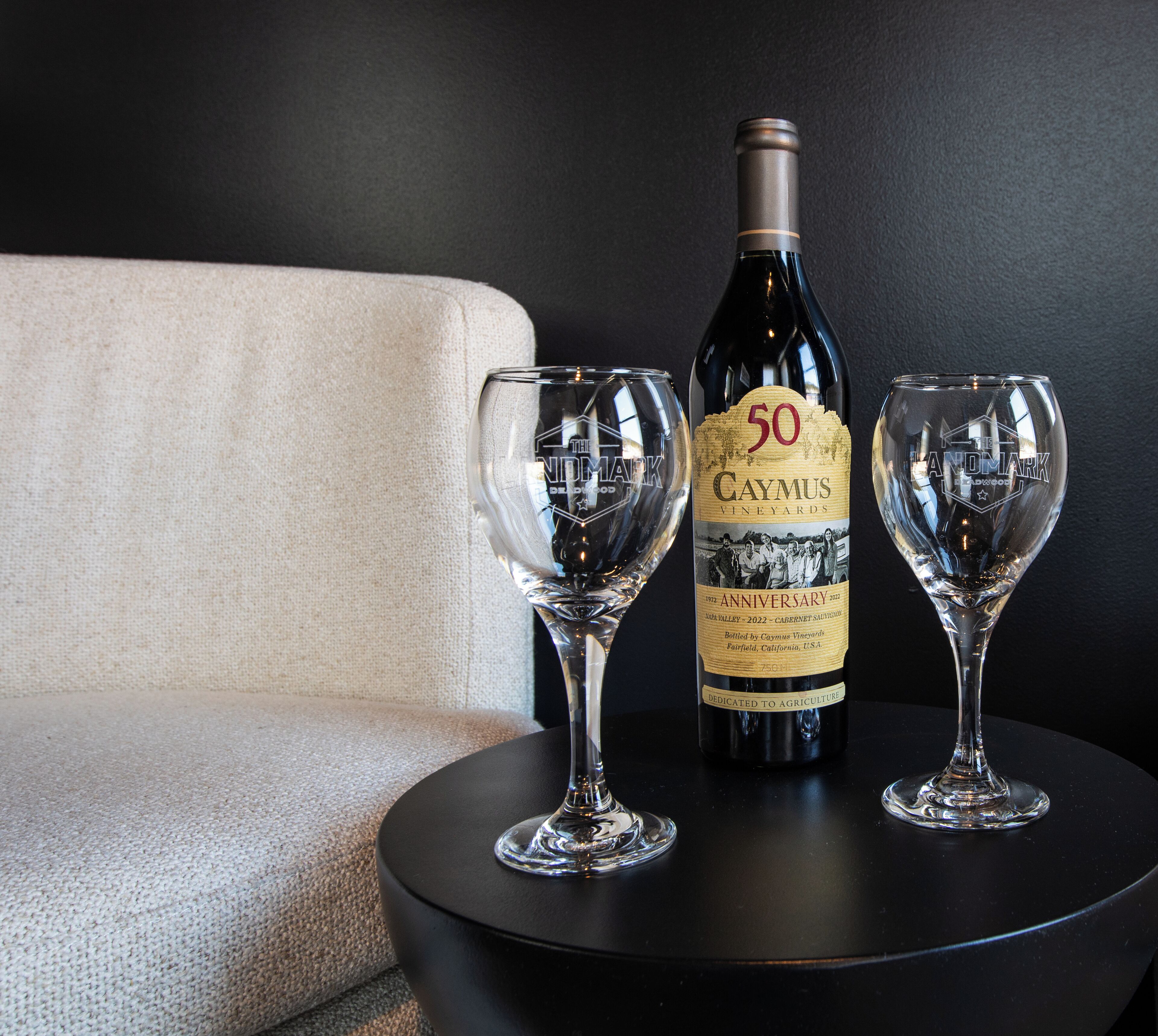 A bottle of wine and two wine glasses on a round black table.