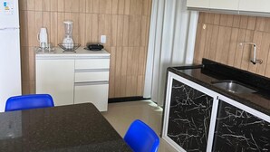 A compact kitchen with a black marble countertop, white cabinets, and blue chairs. - Flat 201 proximo centro Porto de Galinha (Ipojuca)