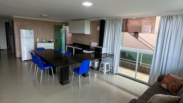A modern kitchen with a dining area, a sofa, and a view of the outside. - Flat 201 proximo centro Porto de Galinha (Ipojuca)