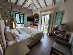 A bedroom with a bed, a desk, a chair, a television, and a window. - Castello di Carlo - Suite Carlo V (Val'Quirico)