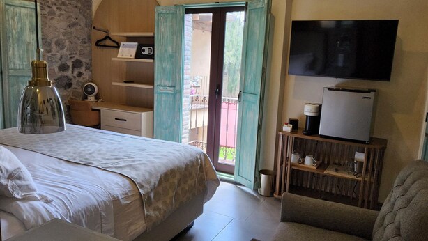 Un dormitorio con cama, escritorio, silla, televisor y refrigerador.
