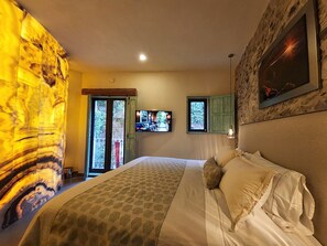 A bedroom with a bed, a television, and a view of the outdoors through a door. - Castello di Carlo - Suite Carlo IV (Val'Quirico)