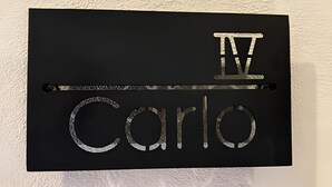 Une plaque noire portant l’inscription « IV Carlos » en lettres métalliques.