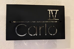 A black sign with the name "IV Carlos" in metallic letters.