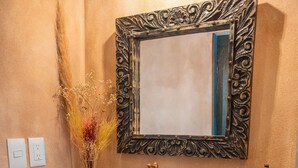 A bathroom with a wooden vanity, a large mirror, and two towels with bird embroidery.