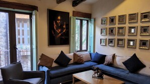 Ein Wohnzimmer mit einer Couch, Sesseln, einem Couchtisch und einer Wand mit gerahmten Bildern.