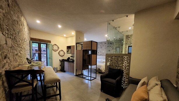 Una sala de estar moderna con sofá, una mesa de comedor con sillas, una zona de cocina y un dormitorio con cama.