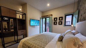 Un dormitorio con cama, televisión, escritorio y ventana.