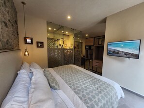Une chambre avec un lit, une télévision et une vue sur la plage.