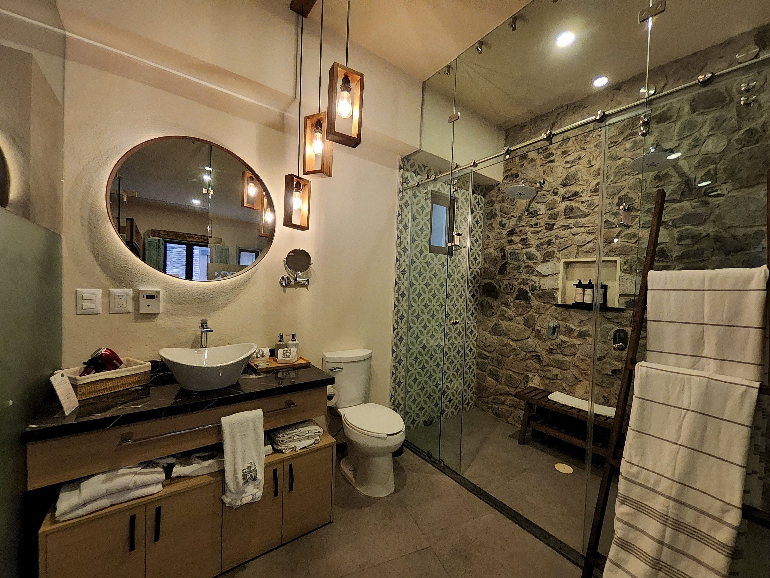 Een moderne badkamer met een grote spiegel, een rond wastafel en een douche met glazen wanden.