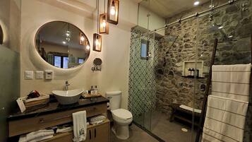 Een moderne badkamer met een grote spiegel, een rond wastafel en een douche met glazen wanden.