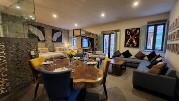 A modern living room with a dining area, a sofa set, and a television.