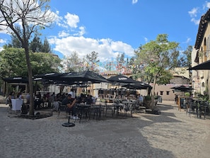 An outdoor café with tables and chairs, surrounded by cobblestone pavement.