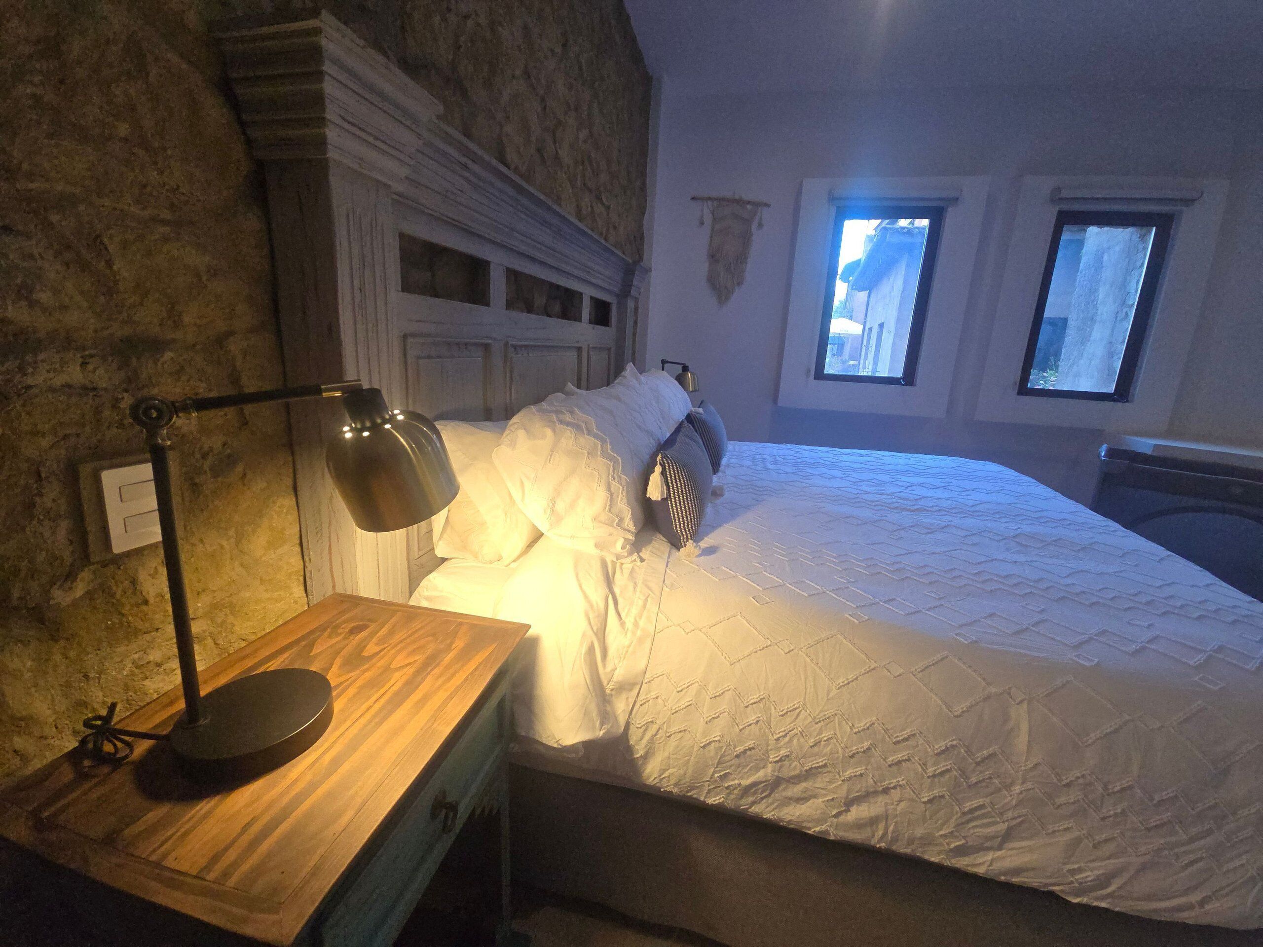 A bedroom with a bed, bedside lamp, and a window.