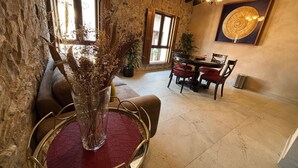 A dining area with a round table, chairs, and a vase of dried flowers.