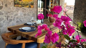 Une table à manger en bois, décorée de fleurs roses, un tableau au mur et des murs en pierre.