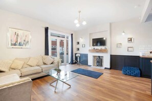 A living room with a sofa, glass coffee table, fireplace, and a television mounted on the wall. - Modern 2 Bedroom Home With TV, WiFi, Parking (Hetton-le-Hole)