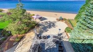 Vista de la playa con un patio, mobiliario exterior y una sombrilla.