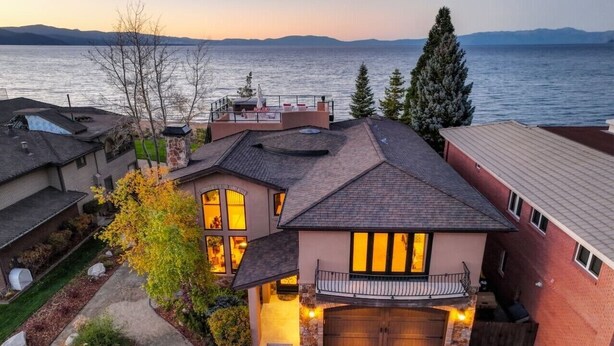 Una casa de dos pisos con garaje, un balcón y vistas al lago.