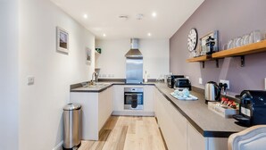 A modern kitchen with a built-in oven, a coffee machine, and a kettle on the counter.