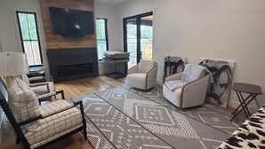 A living room with a fireplace, a ceiling fan, and a large window. - Pet Friendly-newly built house in peaceful  beach community, located in Riva MD. (Riva)