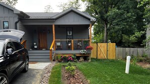 A modern two-story house with a covered porch, a driveway, and a well-maintained garden with a variety of plants and flowers. - Pet Friendly-newly built house in peaceful  beach community, located in Riva MD. (Riva)