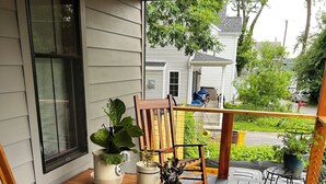 A wooden deck with a table and chairs, potted plants, and a view of a residential street. - Pet Friendly-newly built house in peaceful  beach community, located in Riva MD. (Riva)