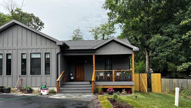 A modern two-story house with a grey exterior, a front porch with wooden railings, and a small garden area with a variety of plants and a flower bed. - Pet Friendly-newly built house in peaceful  beach community, located in Riva MD. (Riva)