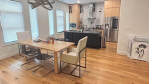 A modern kitchen with a central island, stainless steel appliances, and a dining area with a wooden table and chairs. - Pet Friendly-newly built house in peaceful  beach community, located in Riva MD. (Riva)