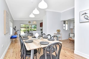Een moderne eethoek met een houten tafel voor zes personen, omringd door zwarte stoelen.