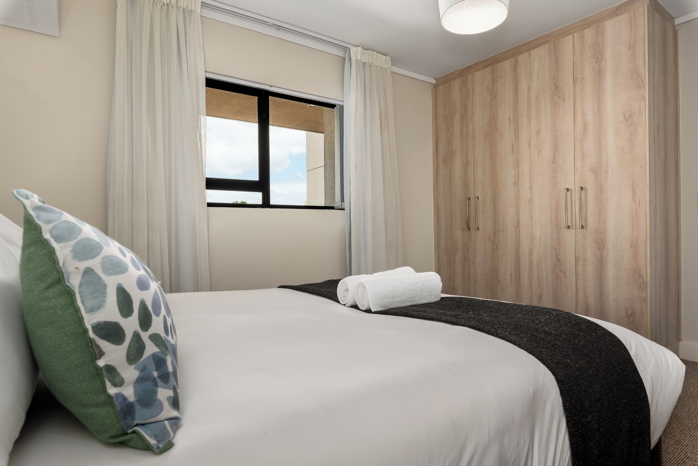 Una habitación de hotel con una cama, una ventana y un armario.